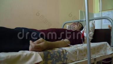 静脉注射。 药物通过静脉注射进入静脉。 医院病房里的一个男人躺在床上。